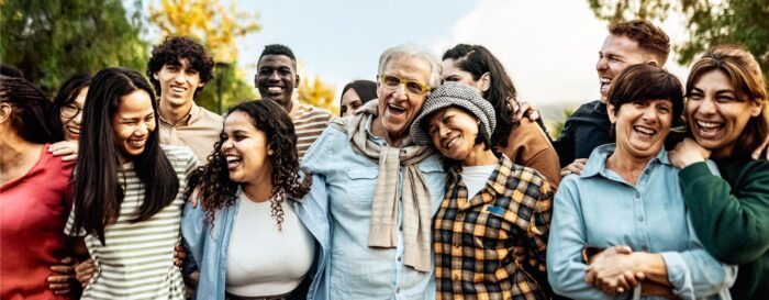 group of individuals hugging and smiling while looking at the camera and themselves